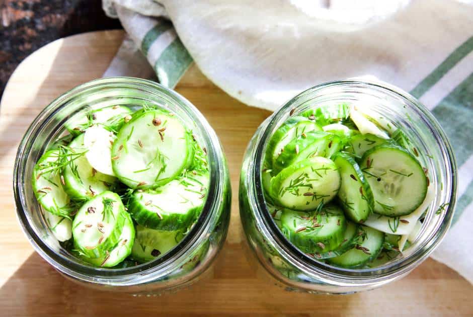 two-open-mason-jars-sliced-persian-cucumbers-garlic-herbs