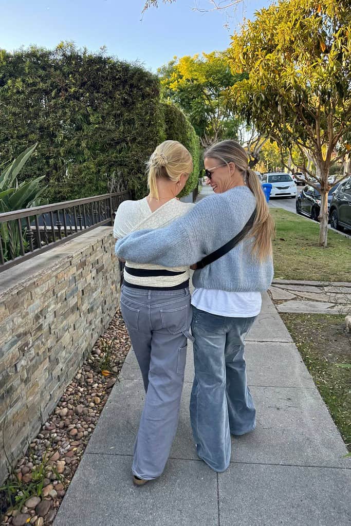 mother-daughter-walking-arm-in-arm-along-sidewalk