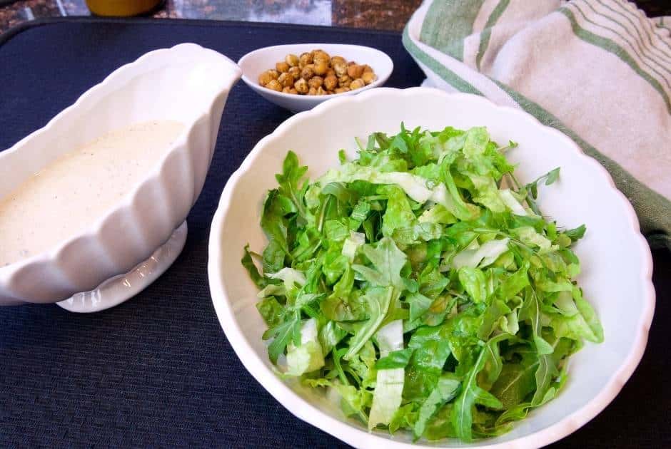 bowl-leafy-greens-caesar-dressing-in-white-gravy-boat-small-dish-roasted-chickpeas