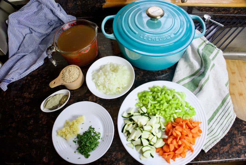 chopped ingredients in dishes and bowls along with a dutch oven in preparation to make lemon rice soup