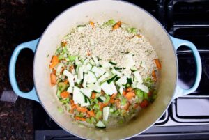 soup ingredients zucchini rice carrots celery onion in dutch oven on stove