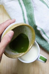 pouring matcha into cup with non-dairy milk