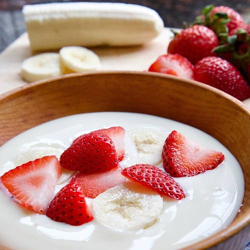 soy yogurt in wooden bowl with strawberries