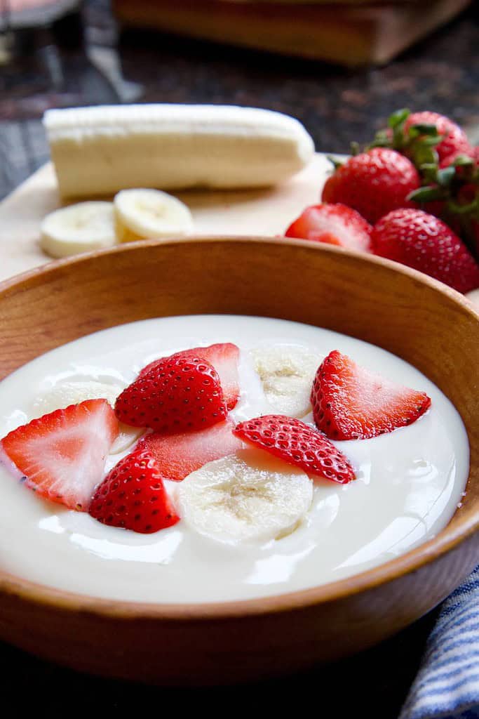 soy yogurt in wooden bowl with strawberries