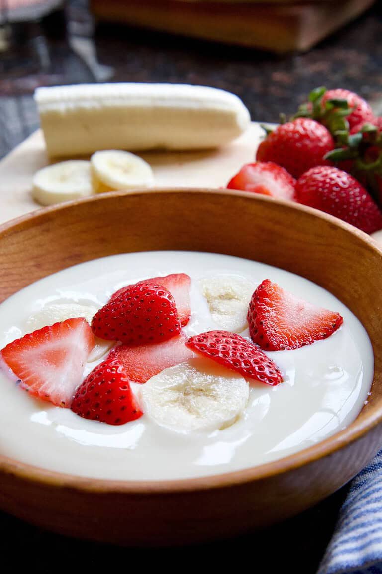 soy yogurt in wooden bowl with strawberries