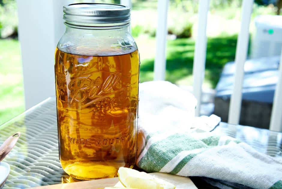 large mason jar with brewed sun tea sitting on a table outside in the sunshine