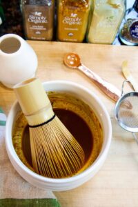 golden latte spices in a white bowl with a whisk