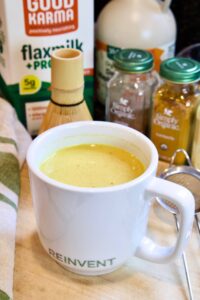 turmeric latte in a white mug with ingredients in the background