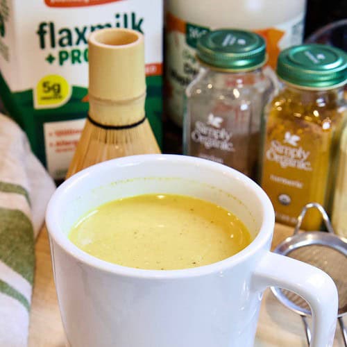 turmeric latte in a white mug with ingredients in the background