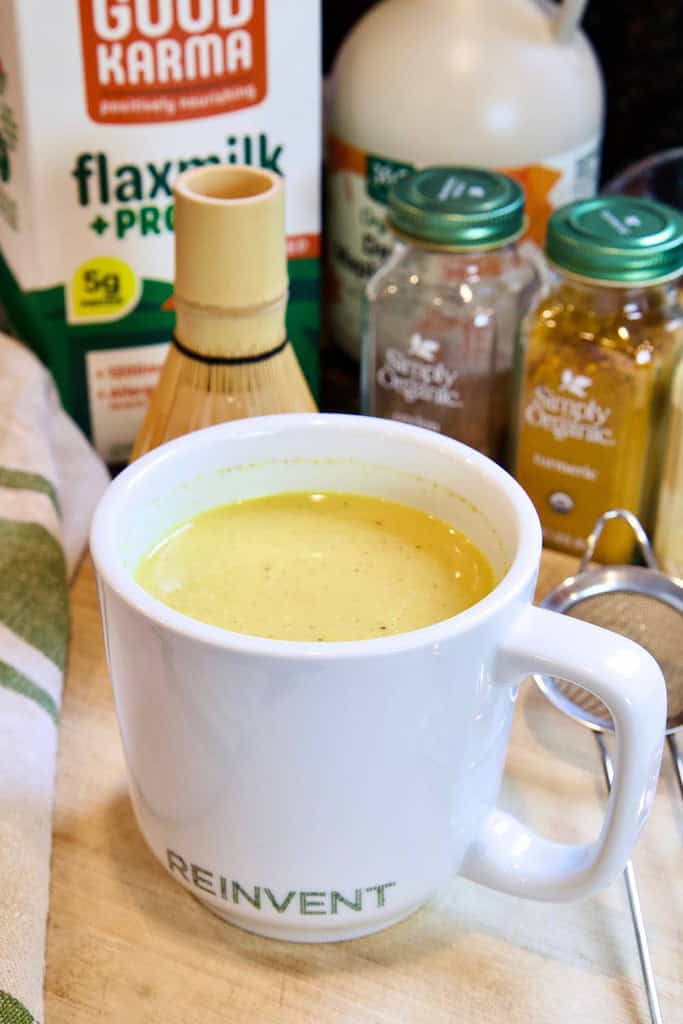 turmeric latte in a white mug with ingredients in the background