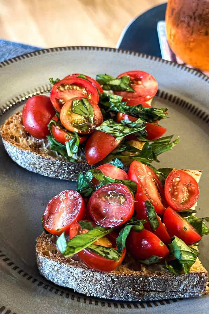 slices of fibrous sourdough toast topped with tomatoes basil and balsamic vinegar