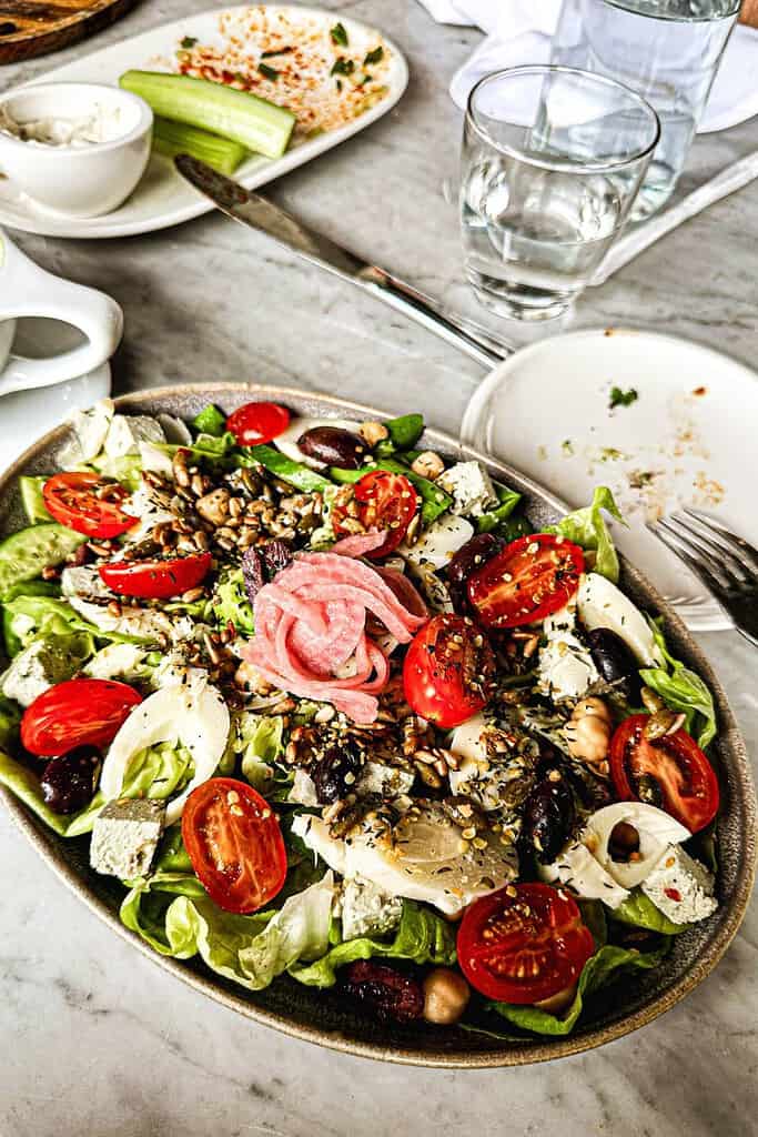 oval salad plate with lettuce tomatoes artichoke hearts sunflower seeds black olives