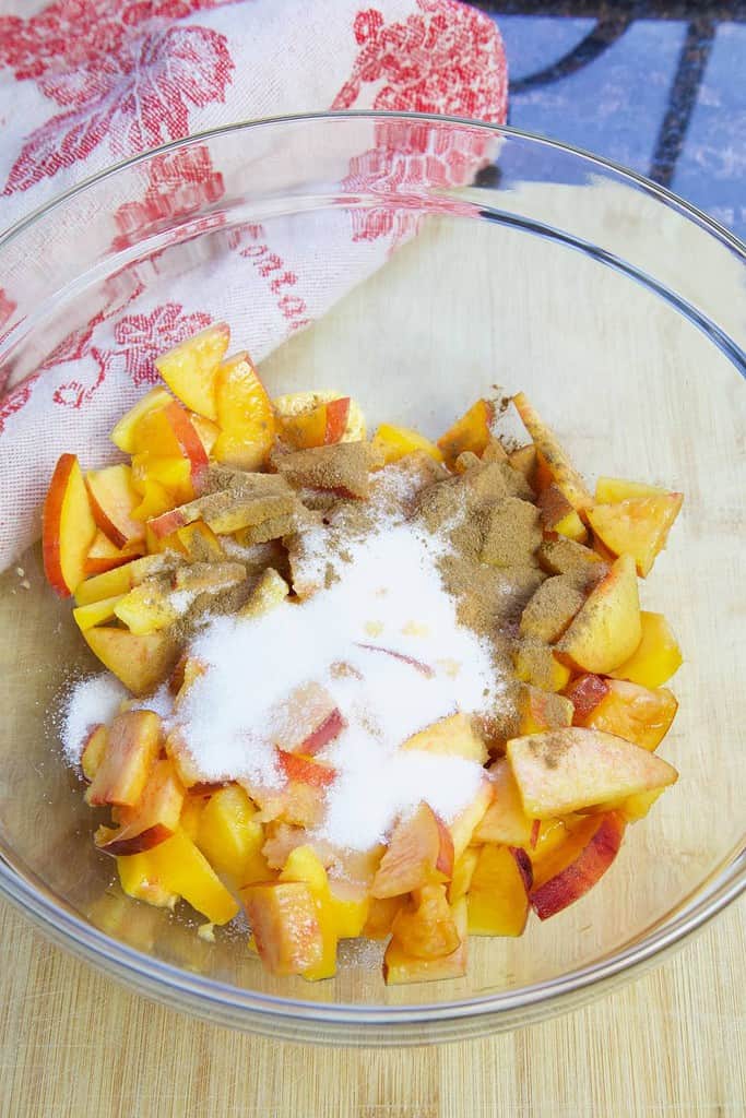 sliced peaches sugar cinnamon in glass bowl