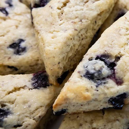 vegan blueberry scones stacked on a white plate