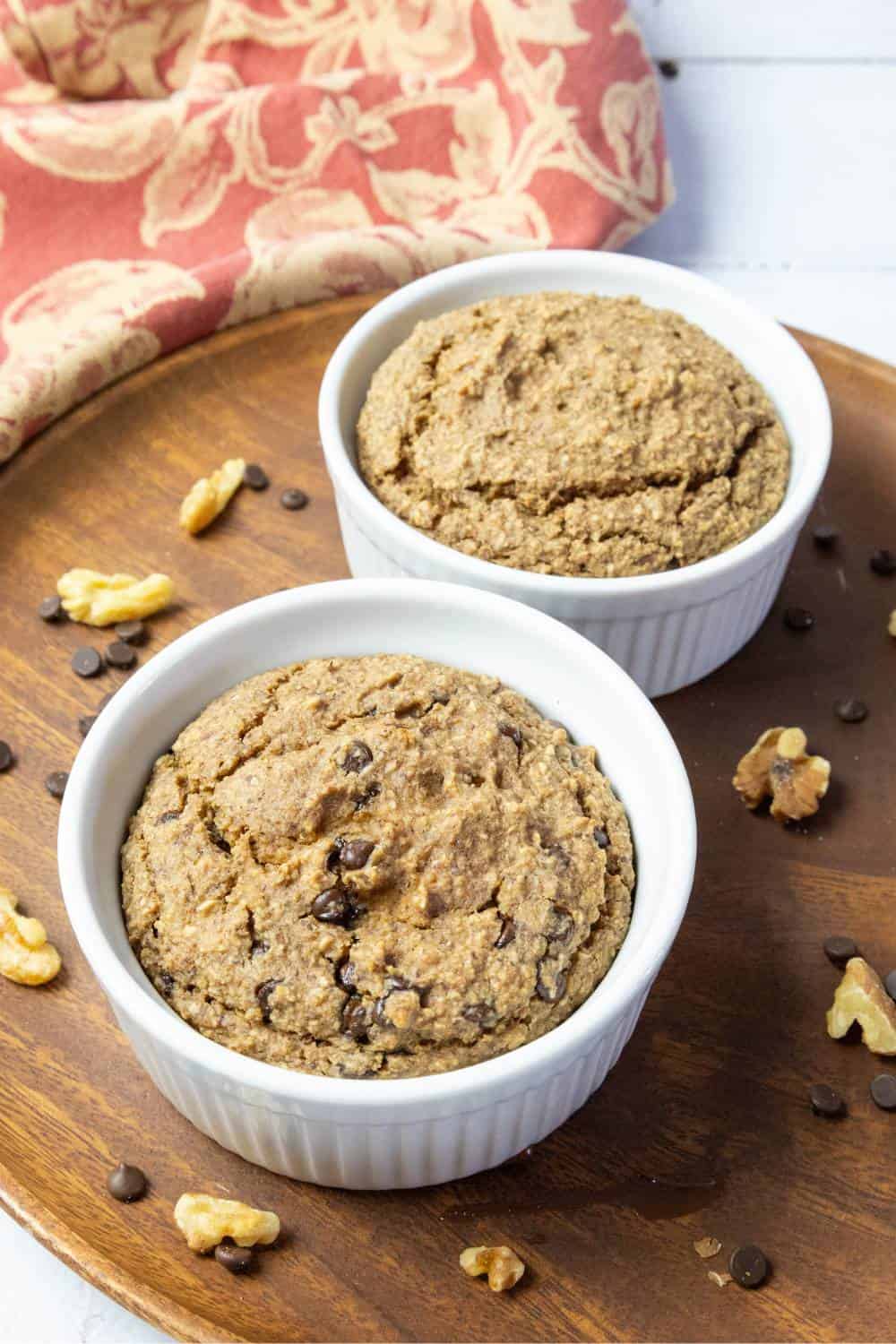 applesauce oatmeal bake in two ramekins on a round wood plate