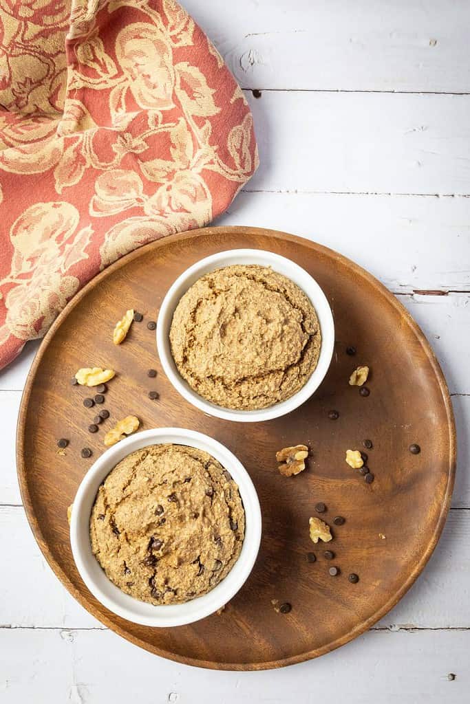 baked oatmeal in two ramekins on a round wood plate