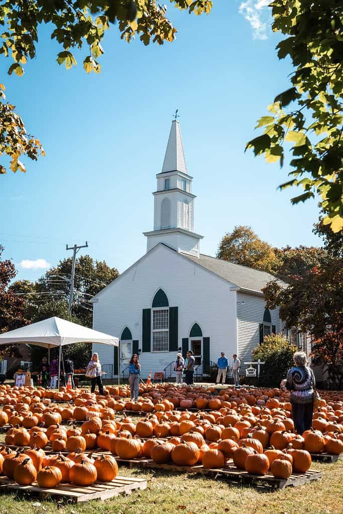 new england in the fall with a pumpkin patch in front of an old historic church