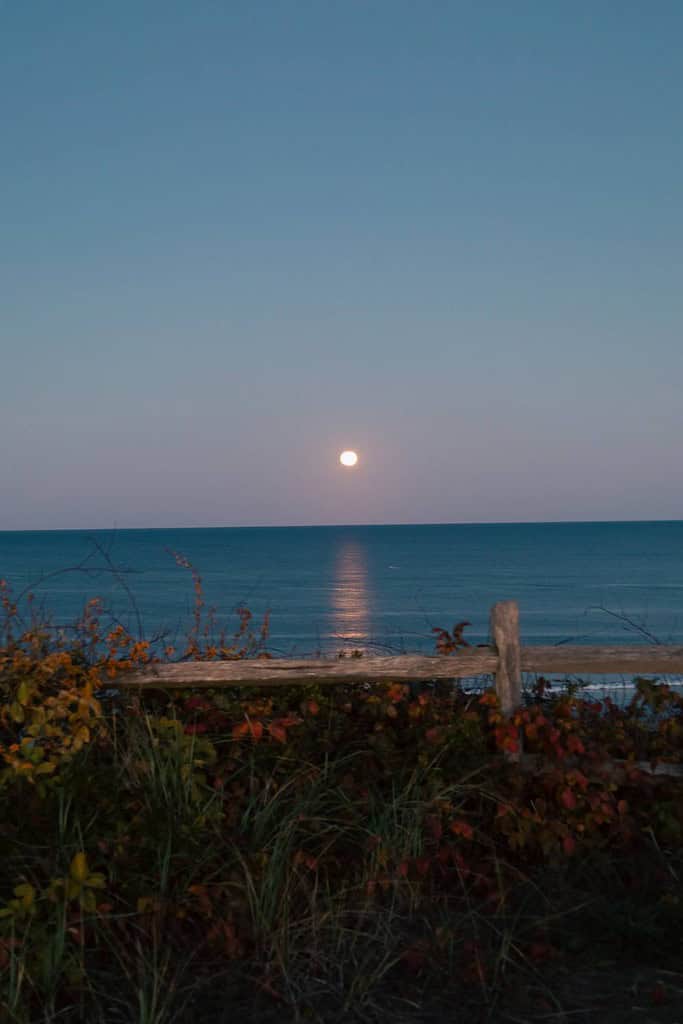 new england in the fall with the sun beginning to set over the ocean