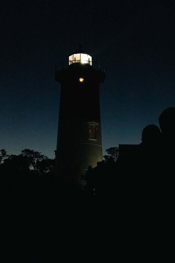 cape cod lighthouse on a hill shining bright in the evening