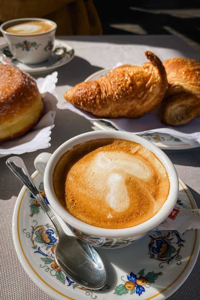 coffee latte in a saucer with a croissant on a small plate