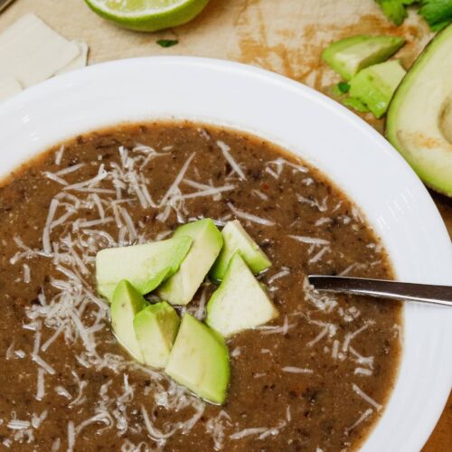 bowl of black bean soup with diced avocado and parmesan cheese