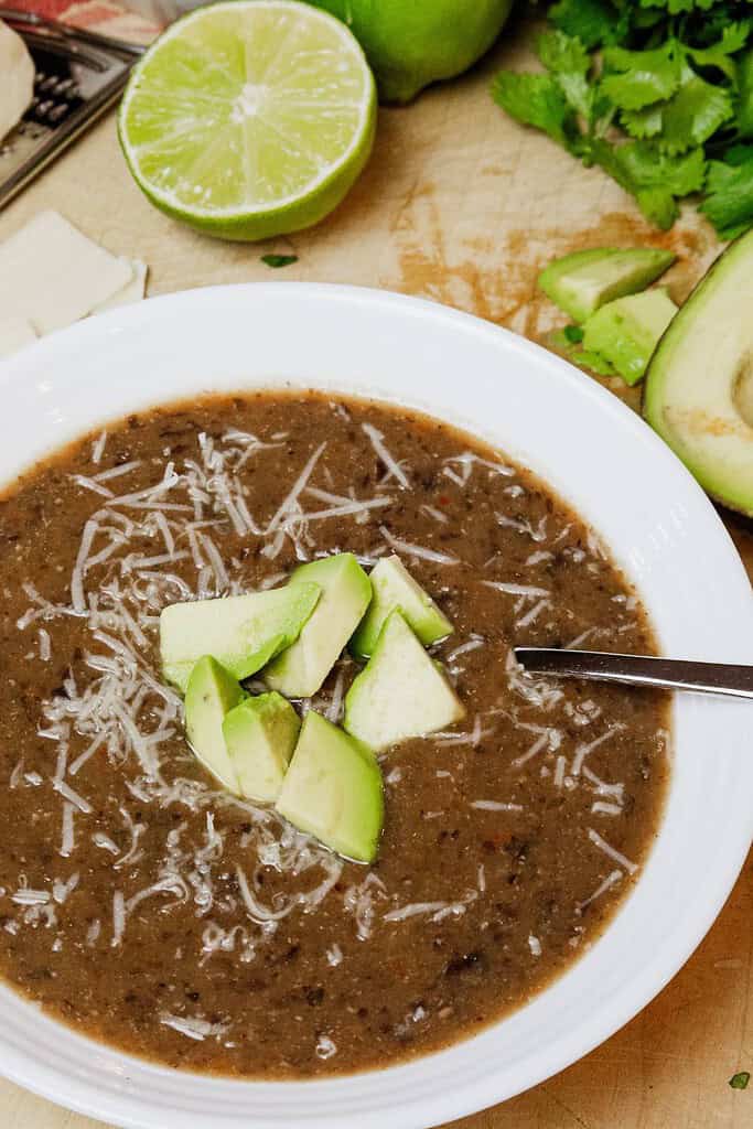 bowl of black bean soup with diced avocado and parmesan cheese