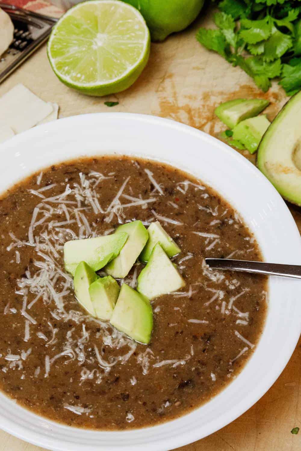 bowl of black bean soup with diced avocado and parmesan cheese