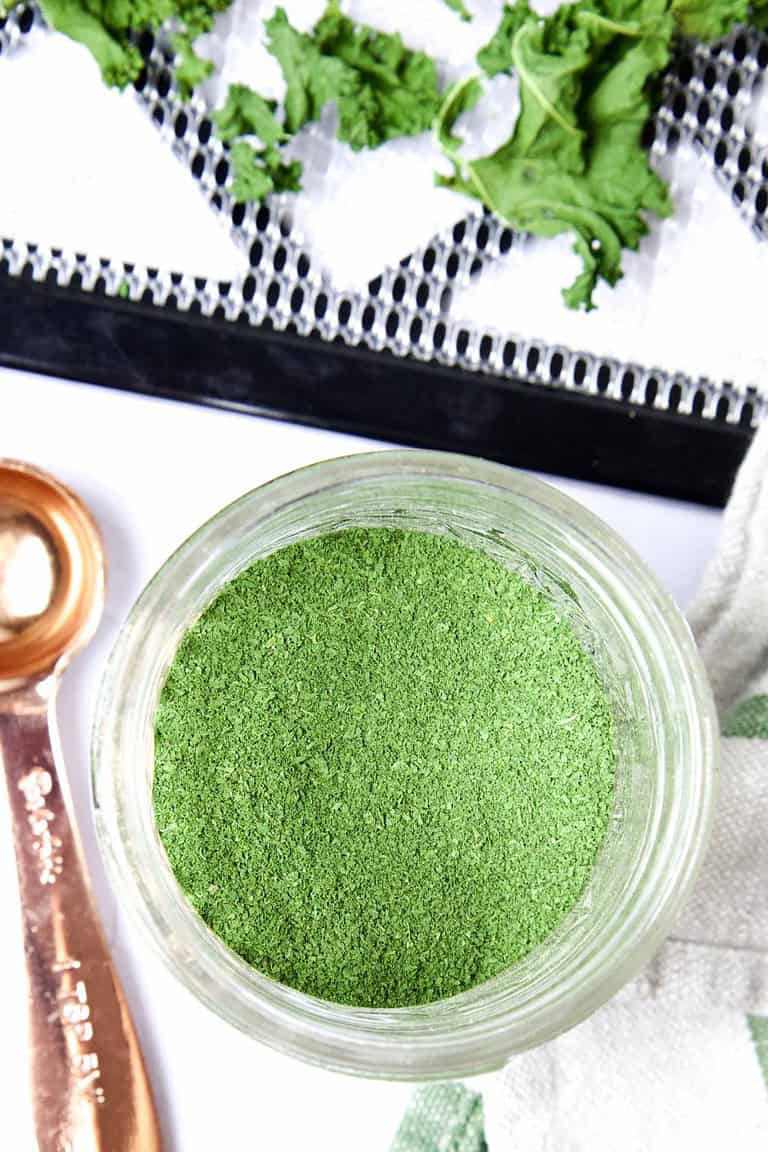 diy green powder in an open glass jar with a copper measuring teaspoon next to it