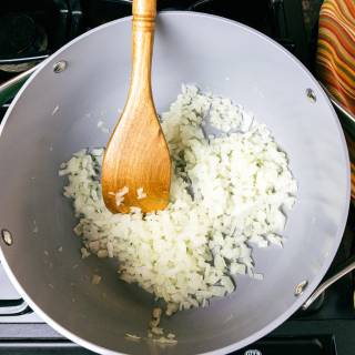 a diced onion being sauteed in a large soup pot