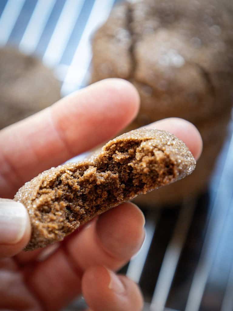 womans hand holding a half eaten cookie