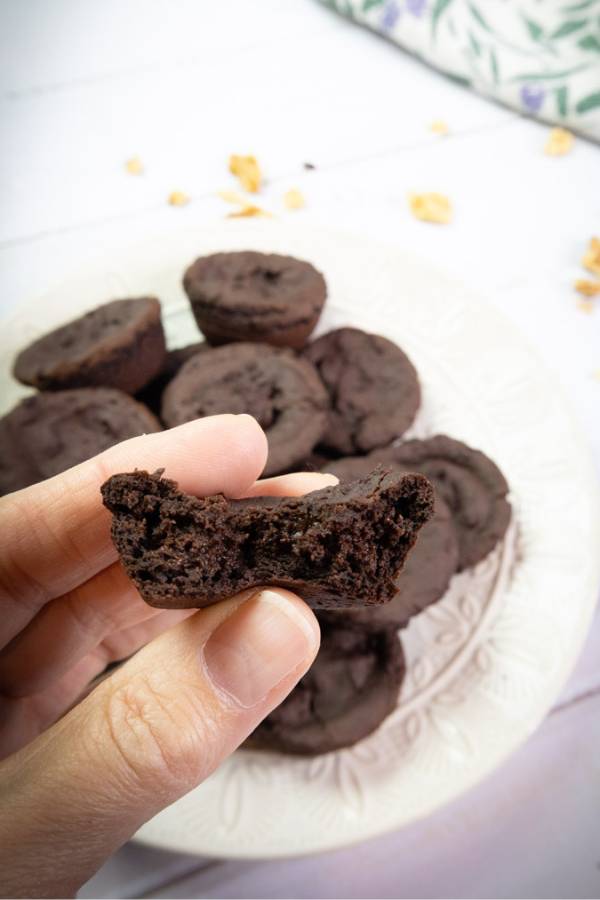 plate of black bean brownies with a woman showing the inside of half a brownie