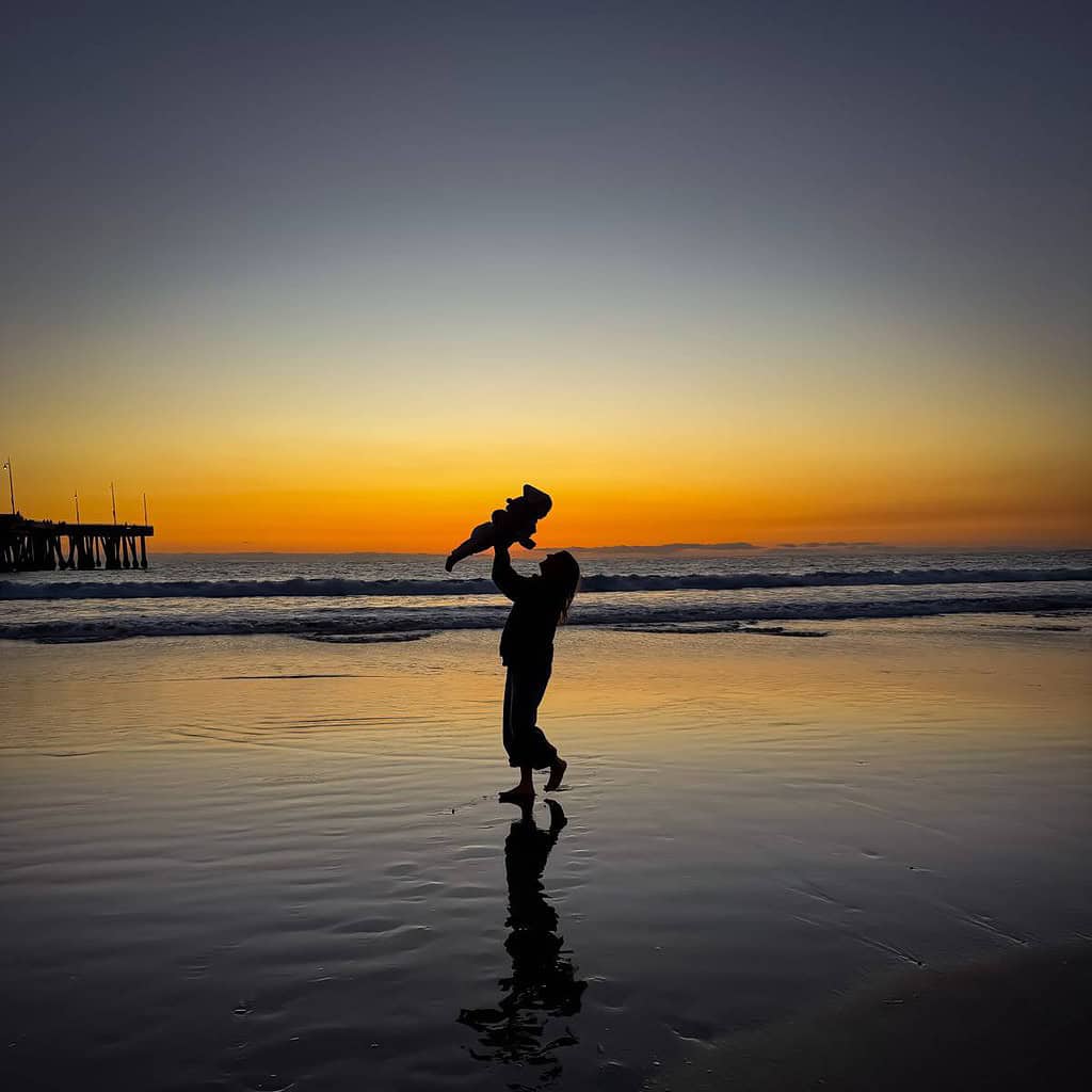 self-care-sunday-woman-at-beach-with-child