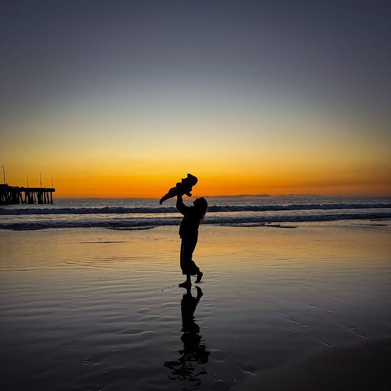 self-care-sunday-woman-at-beach-with-child