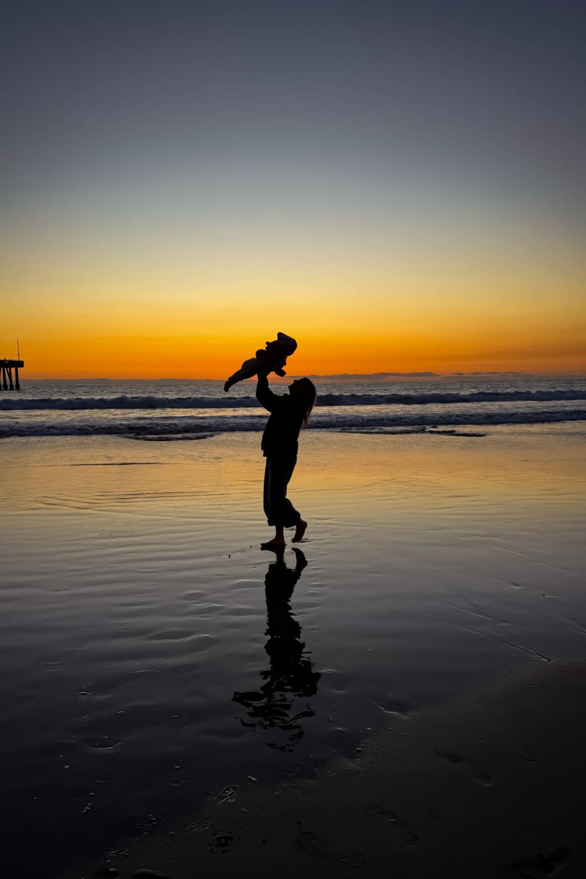 woman-on-beach-with-baby-in-the-air