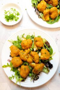 two-plates-with-vegan-buffalo-wings-on-top-of-leafy-greens