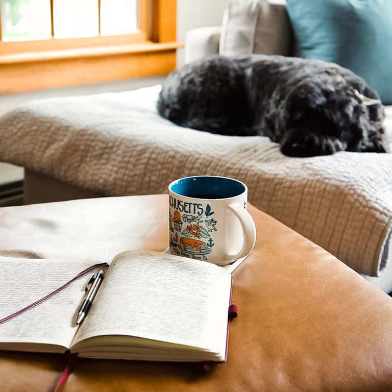 morning-routine-with-journal-coffee-and-black-dog-sleeping-on-couch